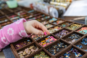 Pesciolini di vari colori, mano di bambina che prende e mostra un pesciolino di gioiello