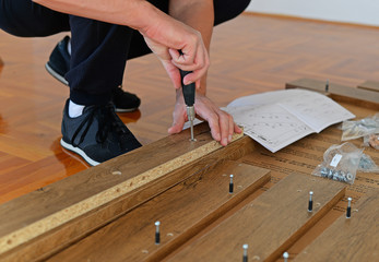 A screwdriver in the hands of workers, working with wood furniture