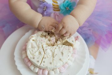 first cake. pink cake. the child takes the cake with his hand. hand in pastry cream. children's holiday