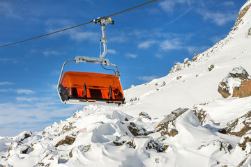Ski lift ropeway on hilghland alpine mountain winter resort on bright sunny day. Ski chairlift cable way with people enjoy skiing and snowboarding. downhill slopes and virgin snow off-piste area