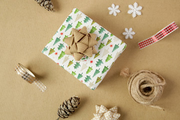 Fototapeta na wymiar Wrapping Christmas gift on the table, directly above view on wrapping paper, bows and ribbons, decorative items for wrapping gift boxes 