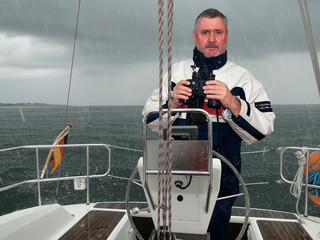A skipper in the rain at the helm of a sailing yacht off the south coast of Sweden. The weather is...