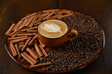 cup of coffee with beans and cinnamon sticks