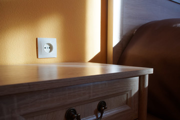 An example of installing an electrical outlet with a European plug next to the bed and bedside table. House, quarter, apartment or hotel