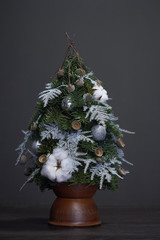 Christmas and New Year composition. Christmas tree made of fir branches and decorated by natural materials and balls in a clay pot