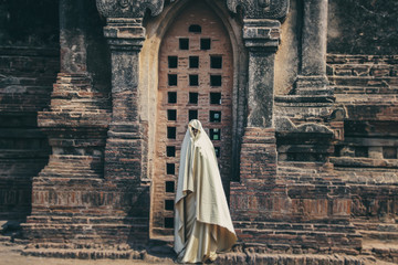 Creature in a gold floaty robe walking along ancient Myanmar Buddhist temples and stupas experimental shoot