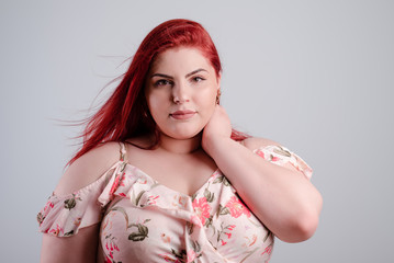 Young obese woman in casual clothes on a white background in the studio. Bodypositive and improper nutrition.