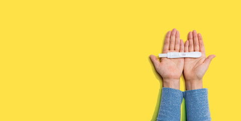 Woman holding a positive pregnancy test - overhead view