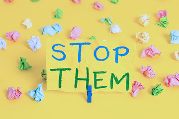 Handwriting text writing Stop Them. Conceptual photo used for telling someone not to do something that they are doing Colored crumpled papers empty reminder white floor background clothespin