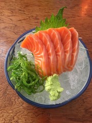 Salmon sashimi, placed in a cup with ice With spicy seaweed and wasabi salad