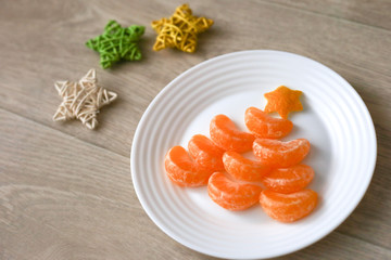 Fruit tangerine Christmas tree on wooden background. New year food background top view. Funny edible Christmas tree. Christmas breacfast idea for kids. Space for text