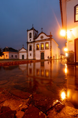 Church in flooded street at night in the historical center of Paraty, Rio de Janeiro, Brazil, World Heritage. Paraty is a preserved Portuguese colonial and Brazilian imperial city.