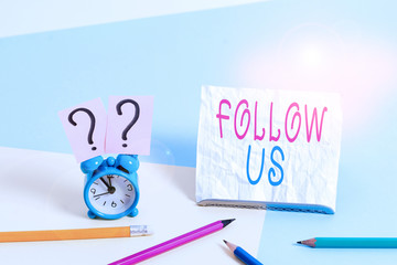 Writing note showing Follow Us. Business concept for To invite a demonstrating or group to join his company and take rules Mini size alarm clock beside stationary on pastel backdrop