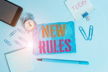 Word writing text New Rules. Business photo showcasing recently one of a set of explicit or understood regulations Alarm clock clips notepad smartphone rubber band marker colored background