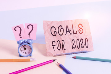 Conceptual hand writing showing Goals For 2020. Concept meaning The following things you want to have and achieve in 2020 Mini size alarm clock beside stationary on pastel backdrop