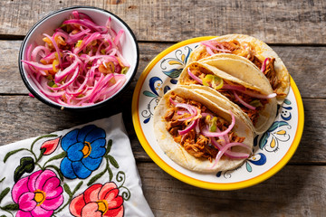 Mexican cochinita pibil tacos with habanero sauce on wooden background
