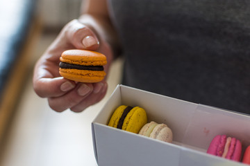 macarons anaranjado en mano de mujer