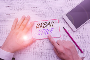 Writing note showing Urban Style. Business concept for fashion that have emerged from the grassroots streetwear Hand hold note paper near writing equipment and smartphone