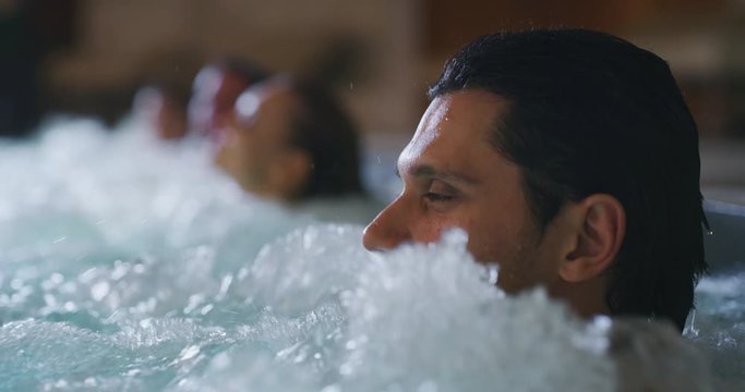 The young happy couples are enjoying their time and having fun in a whirlpool  in a luxury wellness center.
