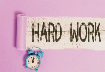 Word writing text Hard Work. Business photo showcasing always putting a lot of effort and care into work or endurance Alarm clock and torn cardboard placed above a wooden classic table backdrop