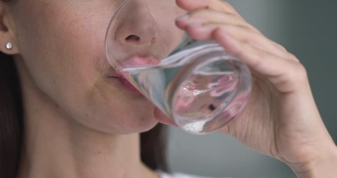 Healthy young lady holding glass drinking water, close up view
