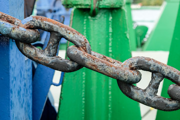 A close up of a very heavy and rusting vessel dock chains to anchor a vessel to the bollards