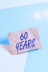 Word writing text 60 Years. Business photo showcasing It is the onset of a golden era Commemorating a special day Paper placed tilted above buffer wire on soft pastel multi colours backdrop