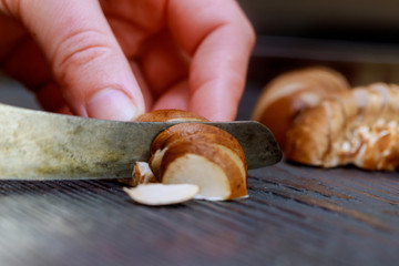 Freshly cut raw uncooked mushrooms sliced with black wooden cutting board