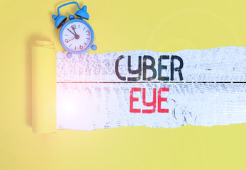 Conceptual hand writing showing Cyber Eye. Concept meaning tool engages in building smart technologies in cybersecurity Alarm clock and torn cardboard on a wooden classic table backdrop