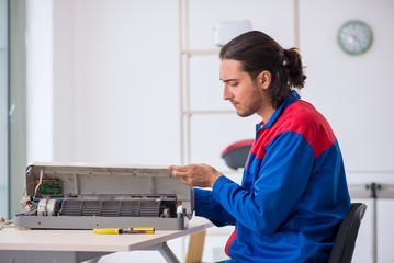 Young male contractor repairing air-conditioner at workshop