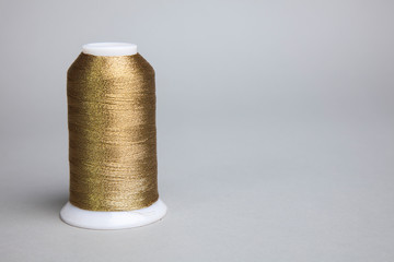 Fototapeta na wymiar sewing thread. a gold fillet standing on it.