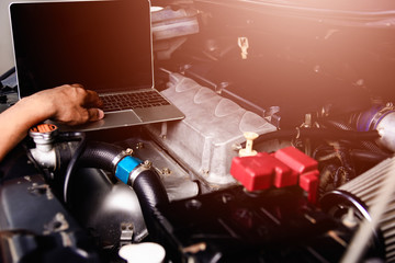 Professional car repair or maintenance mechanic engine working service with laptop computer