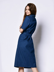 Slender curly female model in a blue urban dress in full growth. Lovely girl in romantic clothes...