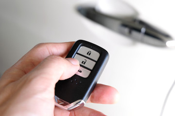 Man hand holding the car remote, he push the remote control to open the car door