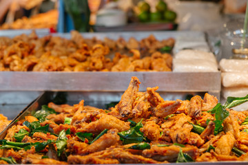 Heap of Thai style deep fried crispy chicken wings for sale in the local street food market in Bangkok, Thailand.