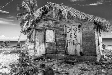 small wooden hut on the beach of the caribbean coast in small fishing village. writing on door in...