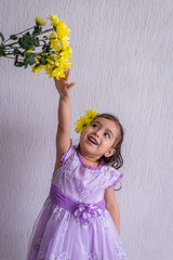 Girl with yellow flowers in her hair, reaches very high flower bouquet