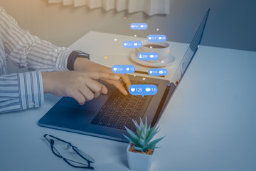 Person using a social media marketing concept on laptop computer with notification icons of like, message, comment and star above laptop keyboard.