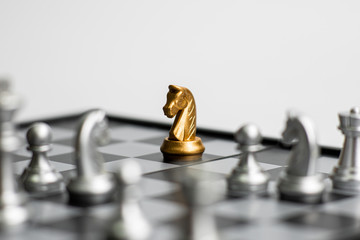 One gold chess pieces staying against full set of chess pieces on white background. Concept leader...