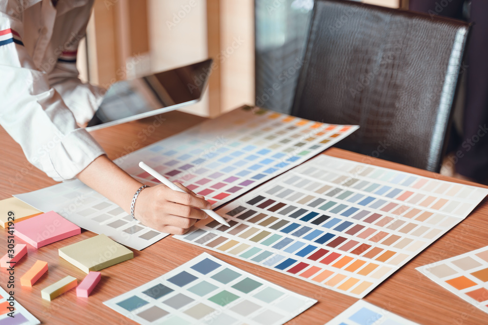 Fototapete creative young graphic designer choosing a color from the sampler and drawing on a digital tablet co