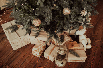 eco-friendly gift boxes in reusable fabric packaging and twine ribbon,in large numbers under the Christmas tree on a dark wooden parquet