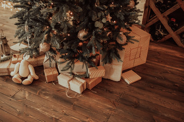 eco-friendly gift boxes in reusable fabric packaging and twine ribbon,in large numbers under the Christmas tree on a dark wooden parquet