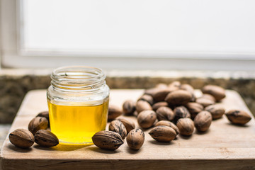 Walnut oil in a jar with nuts on a wooden table