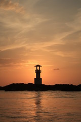 Fototapeta premium Silhouette of a lighthouse during sunset on a beach