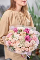 Modern floral shop. Finished work of the florist. Cute bouquet of mixed flowers in womans hands. Delivery fresh cut flower.
