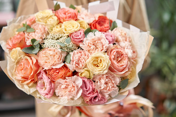 Modern floral shop. Finished work of the florist. Cute bouquet of mixed flowers in womans hands. Delivery fresh cut flower.