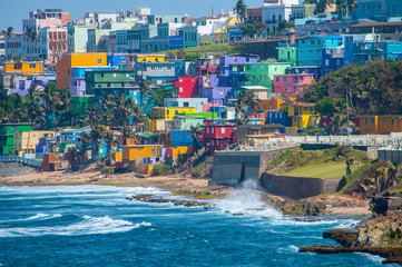 Colorful houses line the hill side overlooking the beach in San Juan, Puerto Rico. - obrazy, fototapety, plakaty