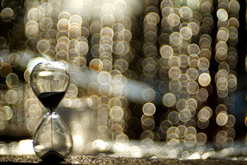 An hourglass with gold bubble blur waterfall in background