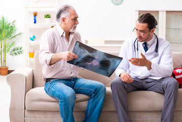 Obraz premium Young male doctor visiting old patient at home