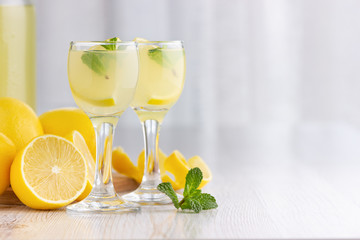 Alcohol cocktail drink with lemon, mint and ice in a small glass.